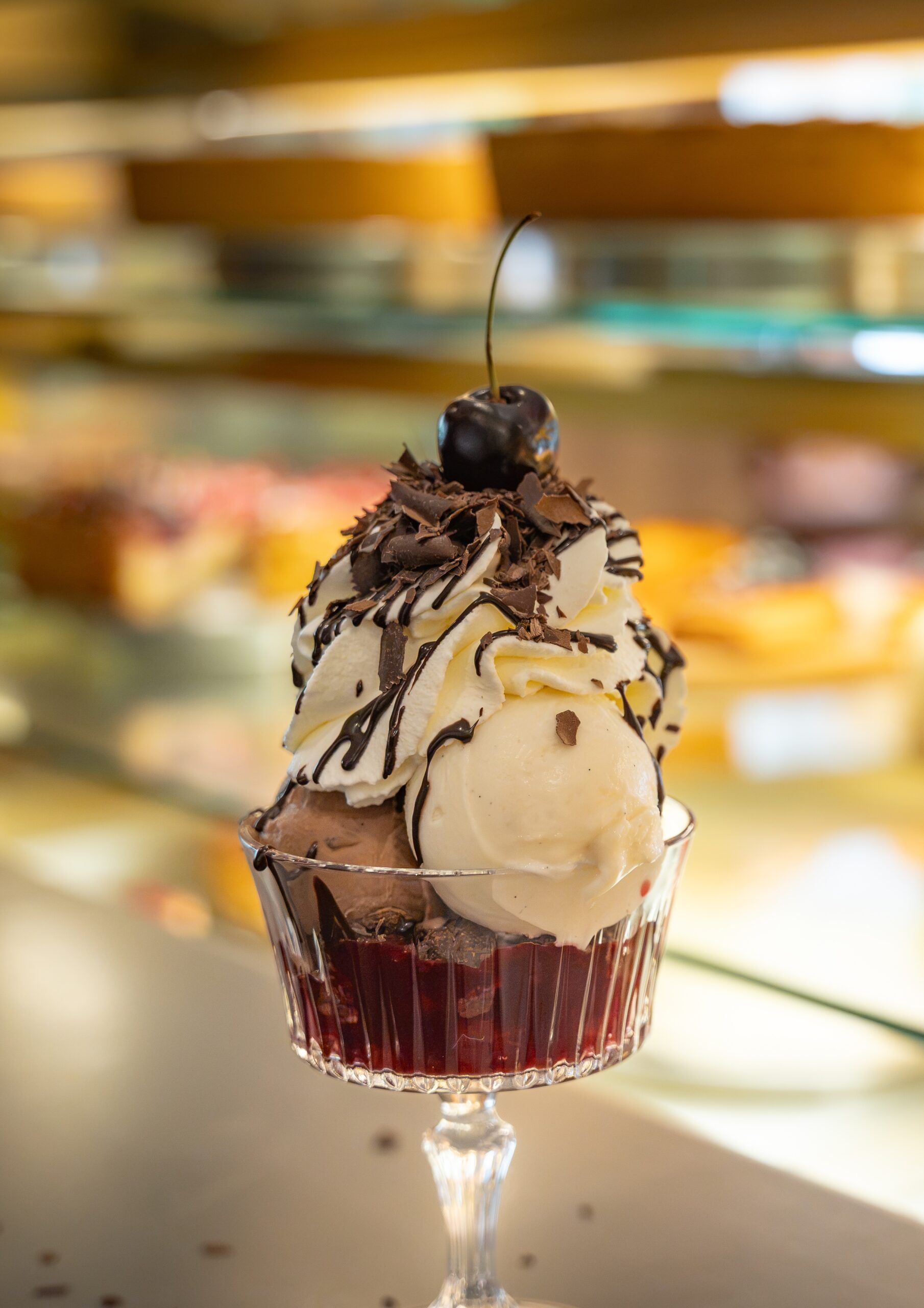 Ein Eisbecher im Cafe Schweigert mit mehreren Kugeln Eis, Sahne, Schokoladensosse und einer Kirsche.
